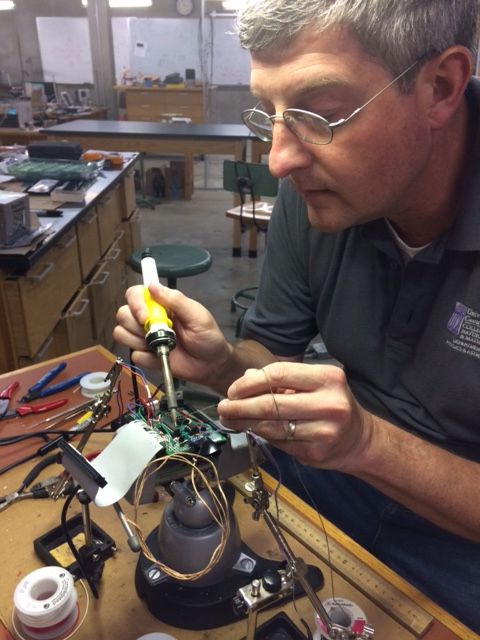 Dr. William Slaton soldering a circuit board in the lab